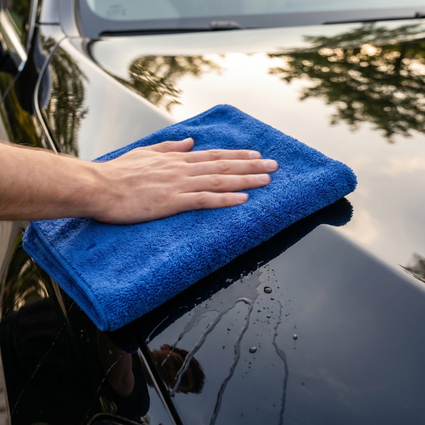DRIVORA XL Microfiber Drying Towel — drying a glossy black luxury car panel, lifestyle